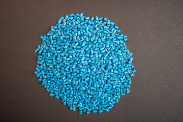 Raw material plastic granules light blue cyan, close-up raw material brown background!