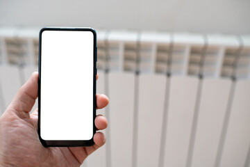 digital smart phone in hand on the blur background of heating radiator