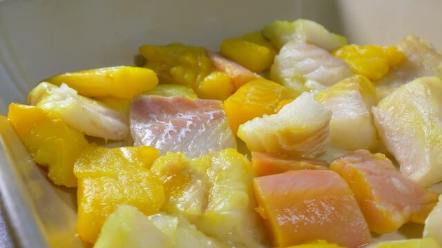 Closeup POV circular dolly shot of pieces of mixed raw fish &ndash; salmon, cod and smoked haddock - in an oven dish, forming the base ingredient for a meal to be baked.