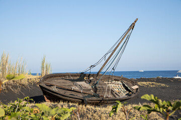 An old abandoned wooden boat on the black volcanic beach. the beauty of the boat remains intact even if tilted by ninety degrees, which helps to make the scenery even more impressive