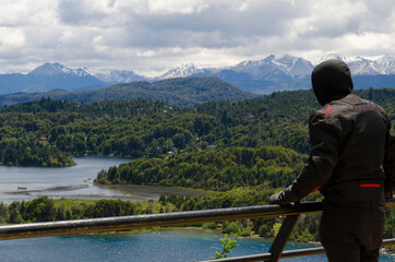 young man looking at the landscape of mountains and lakes in panoramic point in bariloche