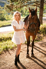 Beautiful woman in a white dress in the forest with a horse