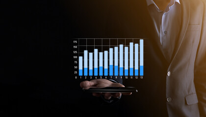 Business man holding holographic graphs and stock market statistics gain profits. Concept of growth planning and business strategy. Display of good economy form digital screen.