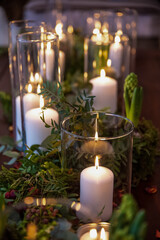 Glass jar's with burning candles ligh the room, making a romantic and warm atmosphere in retro bedroom with nice decoration in background.