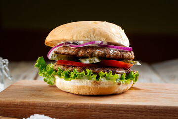 Closeup on double patty burger with pickles on the wooden board