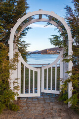 An arched, keyhole shape wooden arbor provides a view across Lake Winnipesaukee and the town of Meredith, New Hampshire, USA.