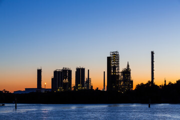 Silhouette at sunset on a clear sky evening of a petroleum processing plant in a river. Sydney, Australia.