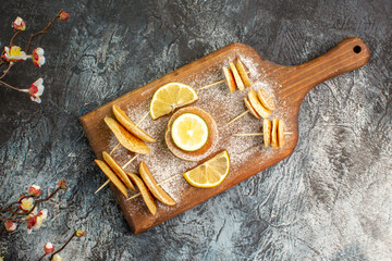 Classic American pancakes with lemons on wooden cutting board with flowers on gray background