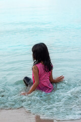 Fototapeta na wymiar Asian little girl happy sitting on the beach in the sea.