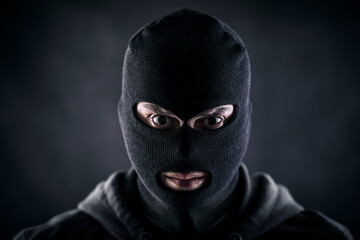 Criminal wearing black balaclava and hoodie in the dark