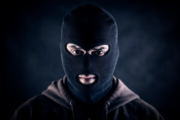Criminal wearing black balaclava and hoodie in the dark
