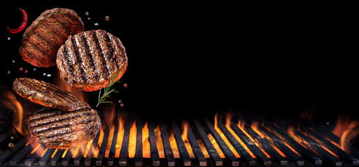 Grilled beef steaks in motion falling down on open grill. Conceptual photo of meat or barbeque cooking process.