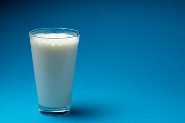 Glass of fresh milk isolated on blue background.