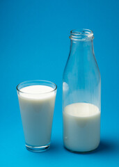 Glass of fresh milk and bottle of milk isolated on blue background.