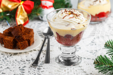 Dessert Black Forest of chocolate sponge cake or brownie with cherries, custard and whipped cream in a glass glass. Trifle. New Year. Christmas. A festive treat for gourmets. Selective focus