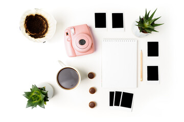 Flat lay analog pink camera, photos, paper notepad and pencil, cup of coffee, hario, succulents on...