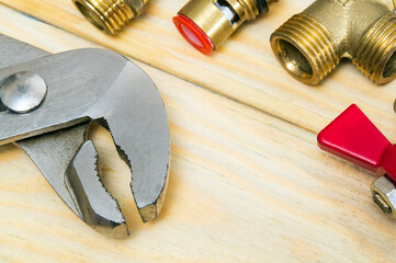 Plumber wrench and brass fittings on wooden boards closeup. Plumbing equipment repair idea concept