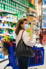 Woman near shopping cart wearing mask in supermarket