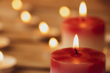 Candles on a wooden background. A red sick candle that changes color when you light it and small candles. Shallow depth of field.