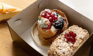 Desserts with custard cream and berries in card box. Selective focus