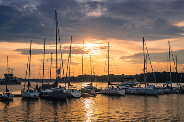 Fototapeta na wymiar Colorful sunset above the sea with sail boats in Germany, Rostock. Reflected sun on a water surface. Seascape, Summer and travel vacation concept