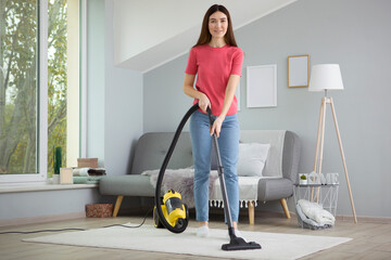 Beautiful young girl in a good mood makes house cleaning with a vacuum cleaner