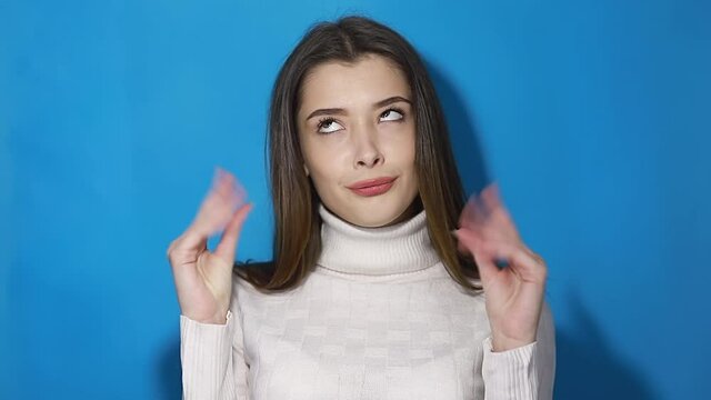 Close up of a young bored woman make blah blah gesture with hand, isolated over a blue background.