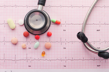 prescription medical pills and stethoscope on a cardio diagram.