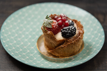 Dessert with custard cream and berries on blue plate. Side view, selective focus