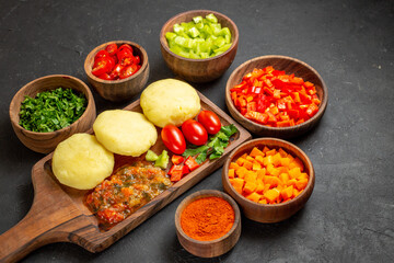 Horizontal view of cooking with fresh vegetables and chopped foods on the black table