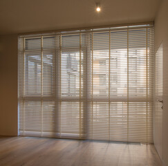 Motorized wood blinds in the interior. Automatic venetian blinds beige color on large windows....