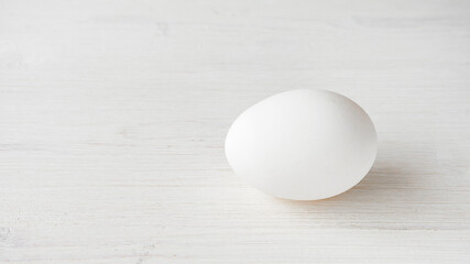 Single whole egg in a white shell on a wooden background