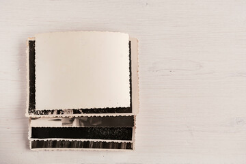 A stack of old photos with an empty reverse side on a wooden background