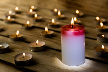Fototapeta na wymiar Candles on a wooden background. A red sick candle that changes color when you light it and small candles. Shallow depth of field.