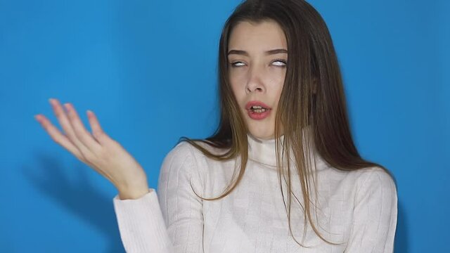 You are crazy, out of mind! Displeased annoyed girl in sweater pointing at camera and showing stupid gesture, blaming some idiot for insane plan. indoor studio shot isolated on blue background