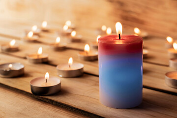 Obraz na płótnie Canvas Candles on a wooden background. A red sick candle that changes color when you light it and small candles. Shallow depth of field.