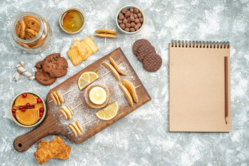 Simple pancakes with lemons on cutting board and cookies honey next to notebook on blue background