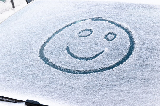 image of a smiling face in the snow on the windshield of a car on a frosty winter day