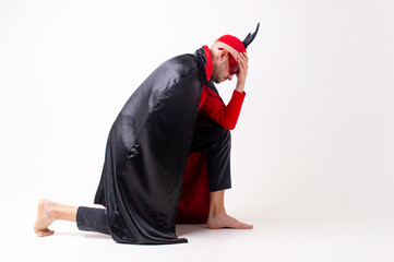 Caucasian male model in halloween black red costume and sunglasses with hat and horns posing over...
