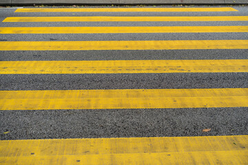 Cars and motorcycles are passing through the pedestrian crossing. Yellow stripes of the crosswalk.