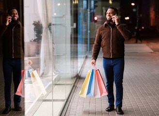 Black man talking on mobile phone holding shopping bag
