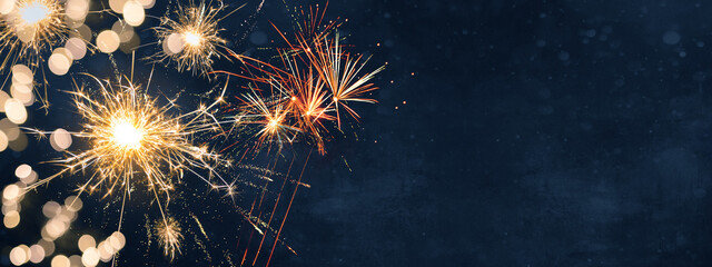 Silvester background banner panorama long- firework and sparklers on rustic dark blue night sky...