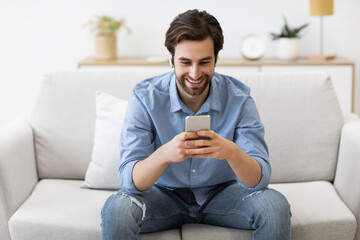 Happy Man In Earbuds Making Video Call On Smartphone Indoors