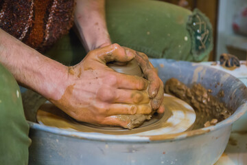 Close up view - professional male potter making pot on pottery wheel at workshop, studio. Handmade,...