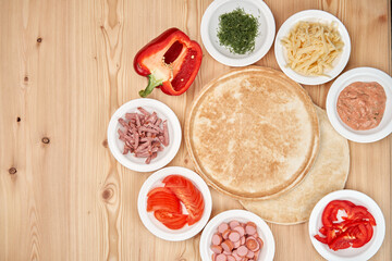 Composition of fresh pizza ingredients on a light wooden background. Cooking pizza. Top view with copy space.