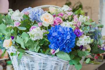 Large floral basket with colorful flowers at workshop, flower shop - close up view. Floristry, holiday, romantic, celebration, handmade and small business concept