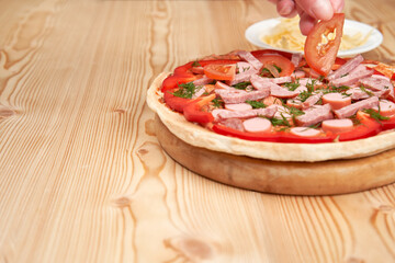 Cook with your hands, lay out the ingredients on the pizza. Close-up with copy space.