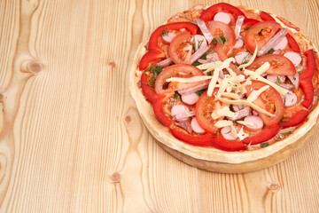 Unprepared pizza with sausage and tomatoes on a wooden board. Homemade food. Top view with copy space.