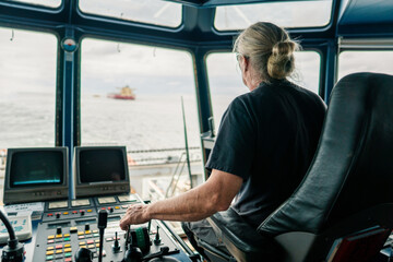 Captain of deck Officer on bridge of vessel or ship during navigaton watch at sea . He is maneuvering with cpp thrusters propulsion and bowthruster