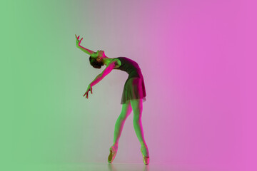 Fototapeta na wymiar Inspired. Young and graceful ballet dancer isolated on gradient pink-green studio background in neon. Art, motion, action, flexibility, inspiration concept. Flexible ballerina, weightless jumps.
